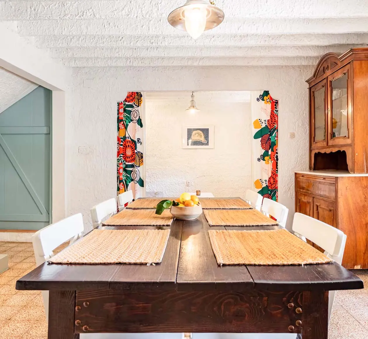 Long wooden dining table with white chairs in the whitewashed dining room of House Agave
