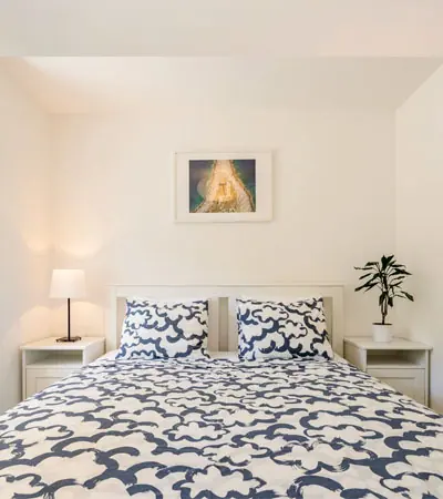 Bedroom with a king size bed, blue patterned linen and bedside lamps