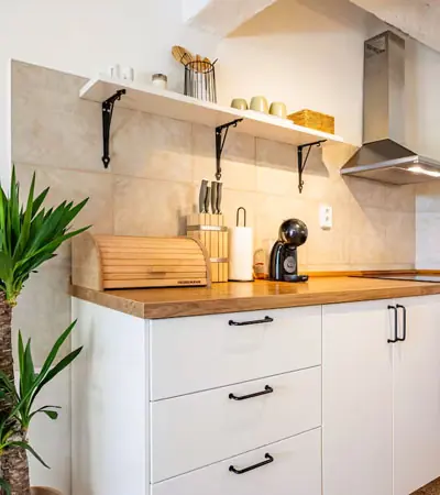 Kitchen with white cabinets, wooden worktop, open shelves and coffee machine