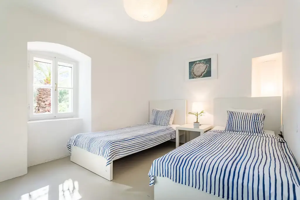 Bright twin bedroom with blue and white striped bedding and an arched window
